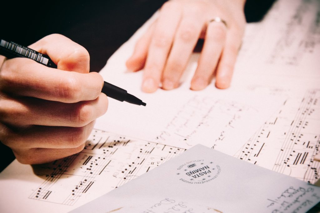 A person practicing their writing habits on a sheet of music.